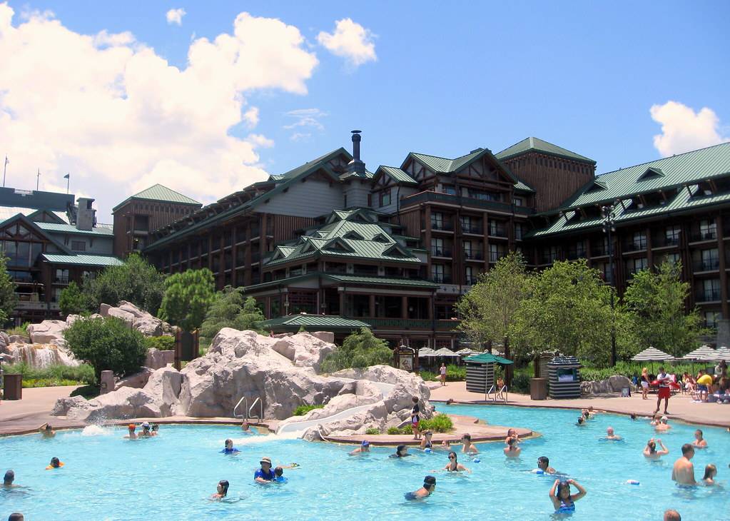 A lot of buildings with pointed roofs with a pool at the front