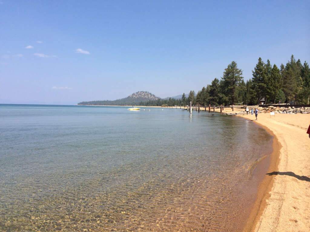 The beach of South Lake Tahoe with the crowds of people, majestic view and blue sky