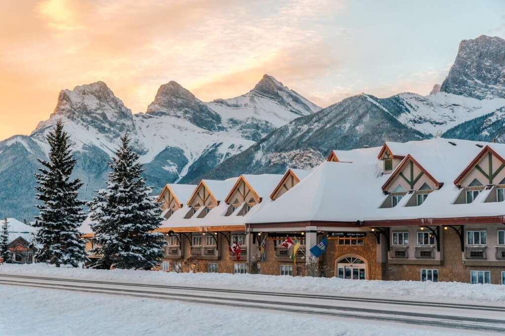 A brown building with snow covered roof at the road side, canmore hotels
