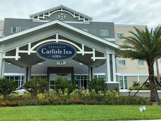 A grey and white building with a green grass land, Sarasota Hotels 