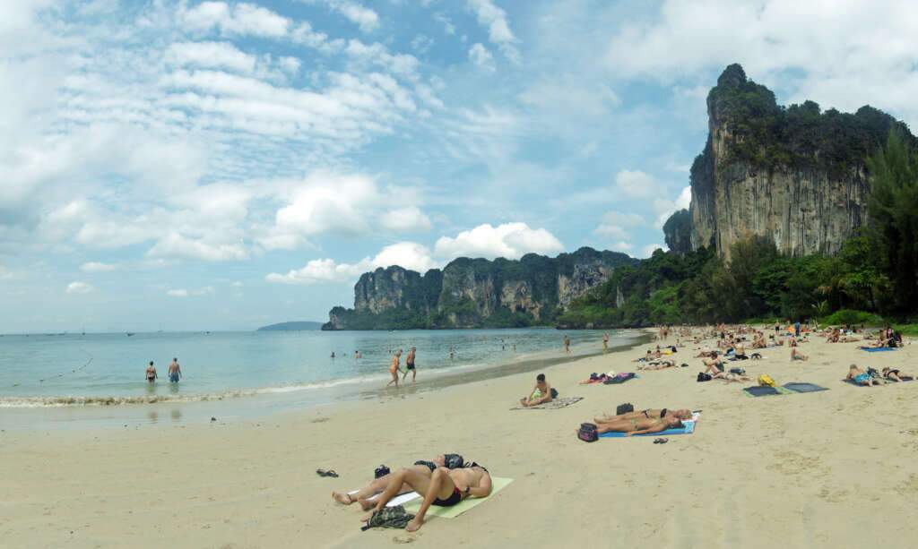 The peoples are enjoying, swimming and hiking on the Railay Beach under the blue sky with clouds