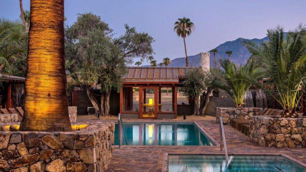 Sparrows Lodge resort a pool surrounded by a stone wall and palm trees.