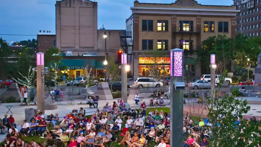 a crowd of people sitting on the grass in front of a building.