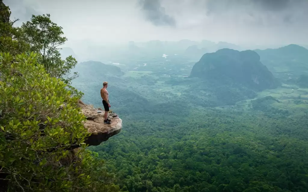 A man is wearing shorts and standing on the top of Khao Ngon Nak and enjoying the beauty