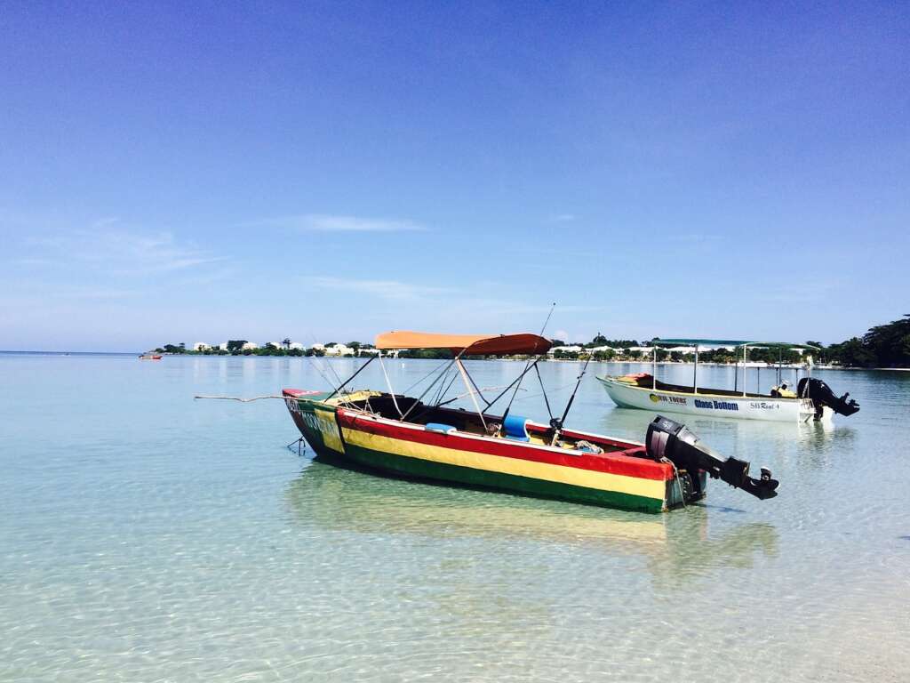 The boats are resting on the body of water on Negril Beach the daylight view
