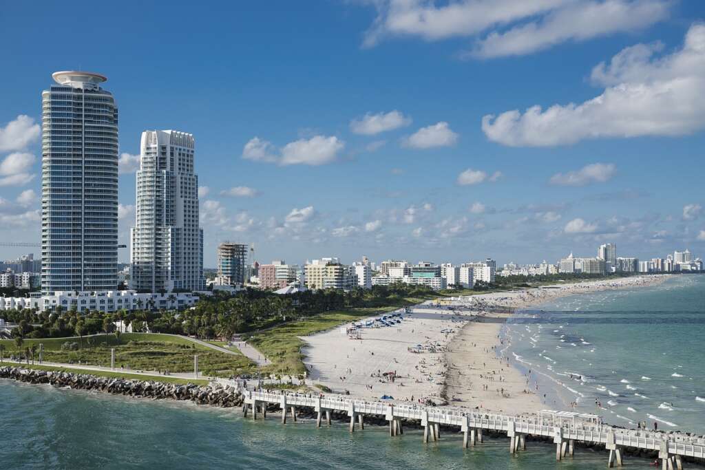 Maimi Beach is full with crowd of people and the water of beach shines under the blue sky