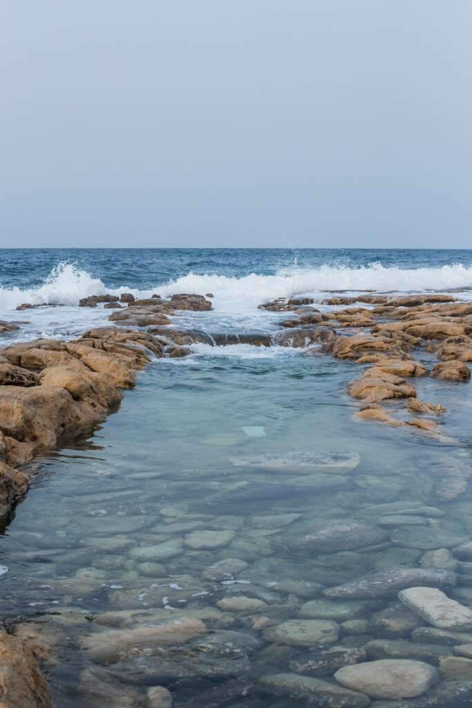 a rocky beach with waves crashing of Sliema under the blue sky looks beautiful. Sliema is a great choice for where to stay in Malta because it has a ton of both.