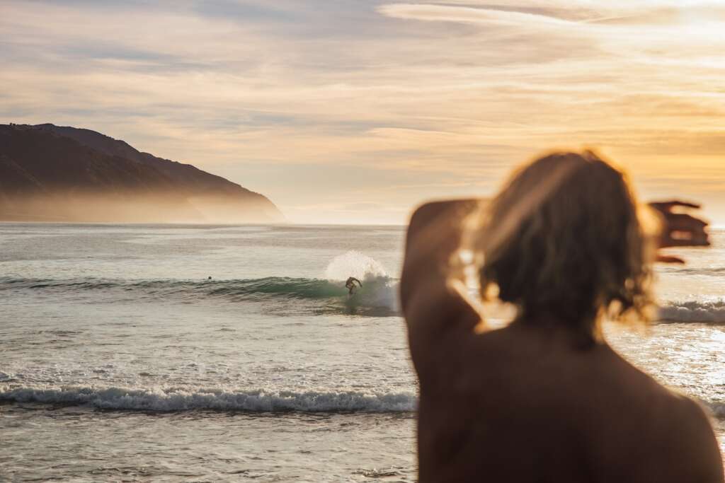 person covering eyes in front of body of water and enjoying summer is one of the best time to visit New Zealand